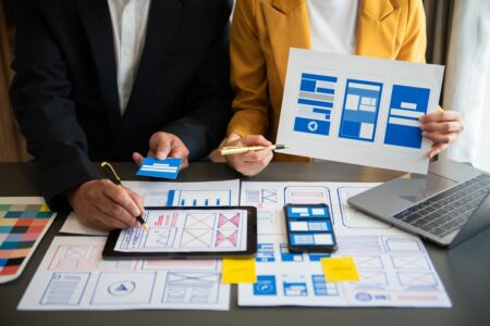 UX developer and ui designer brainstorming about mobile app interface wireframe design with customer breif and color code at modern office.