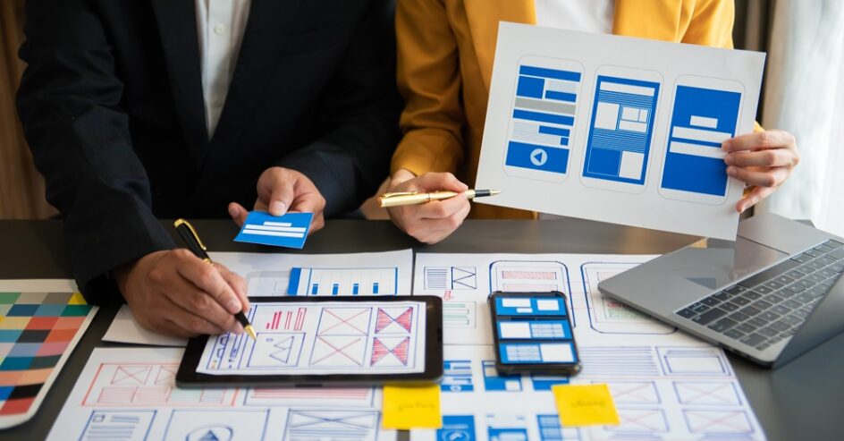 UX developer and ui designer brainstorming about mobile app interface wireframe design with customer breif and color code at modern office.
